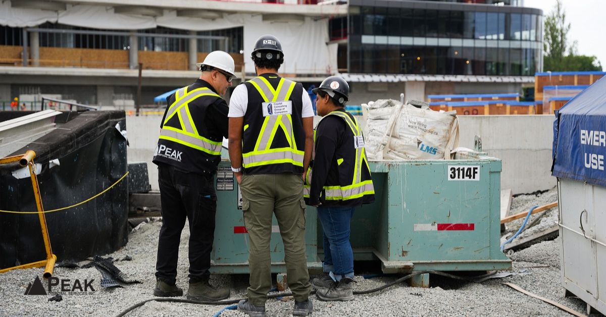 Peak Disposal team reviews site conditions beside a construction bin during an active project coordination visit.