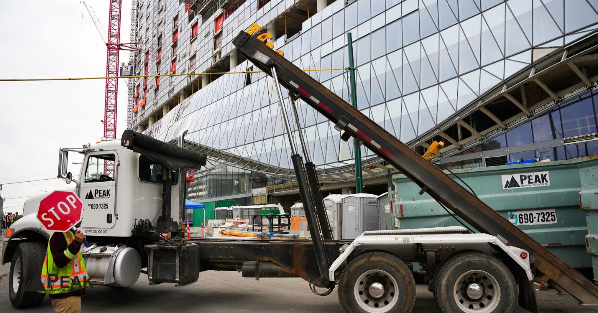 Peak Disposal roll-off truck delivers a bin at an active high-rise construction site safely.